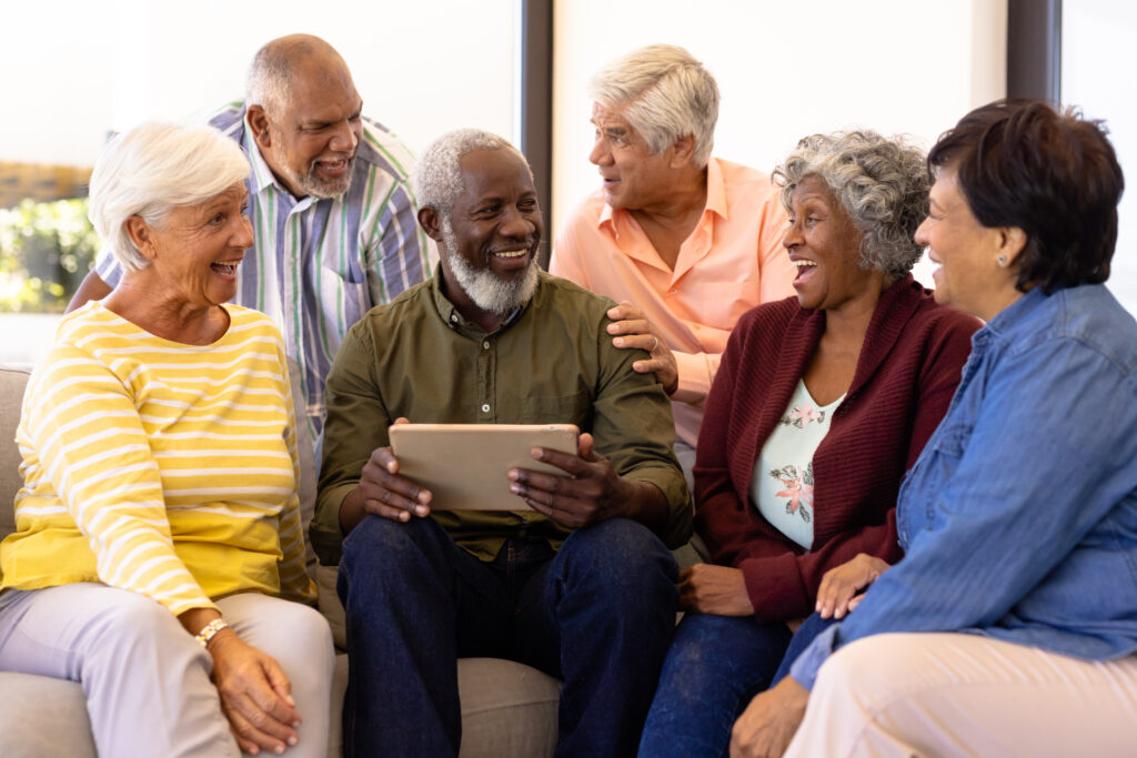 Multiracial senior man holding digital tablet looking at laughin